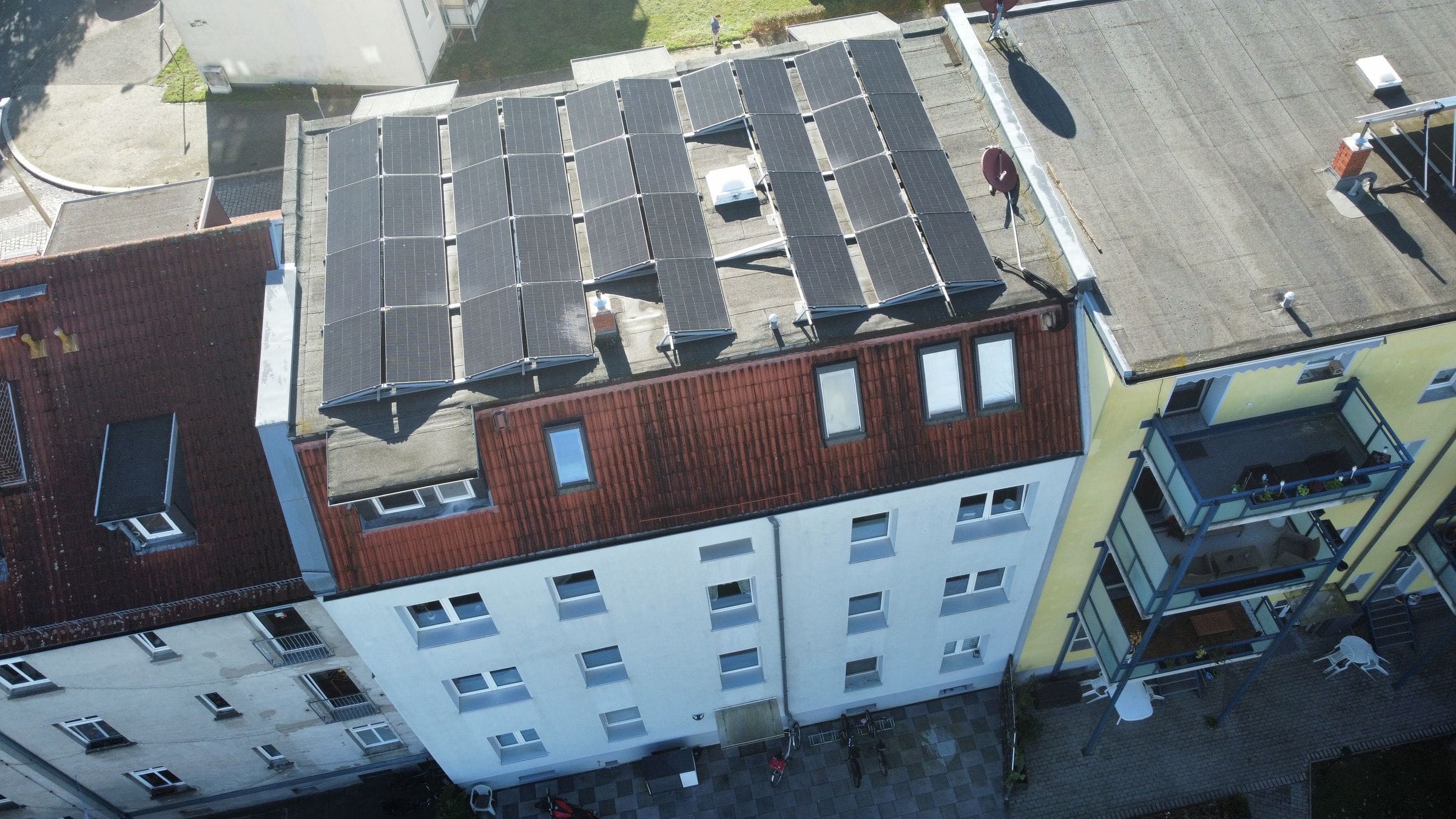 Drohnenaufnahme eines Mehrfamilienhauses in Dessau mit aufgeständerten schwarzen Solarmodulen auf dem Flachdach, gebaut von DKZ-Solar